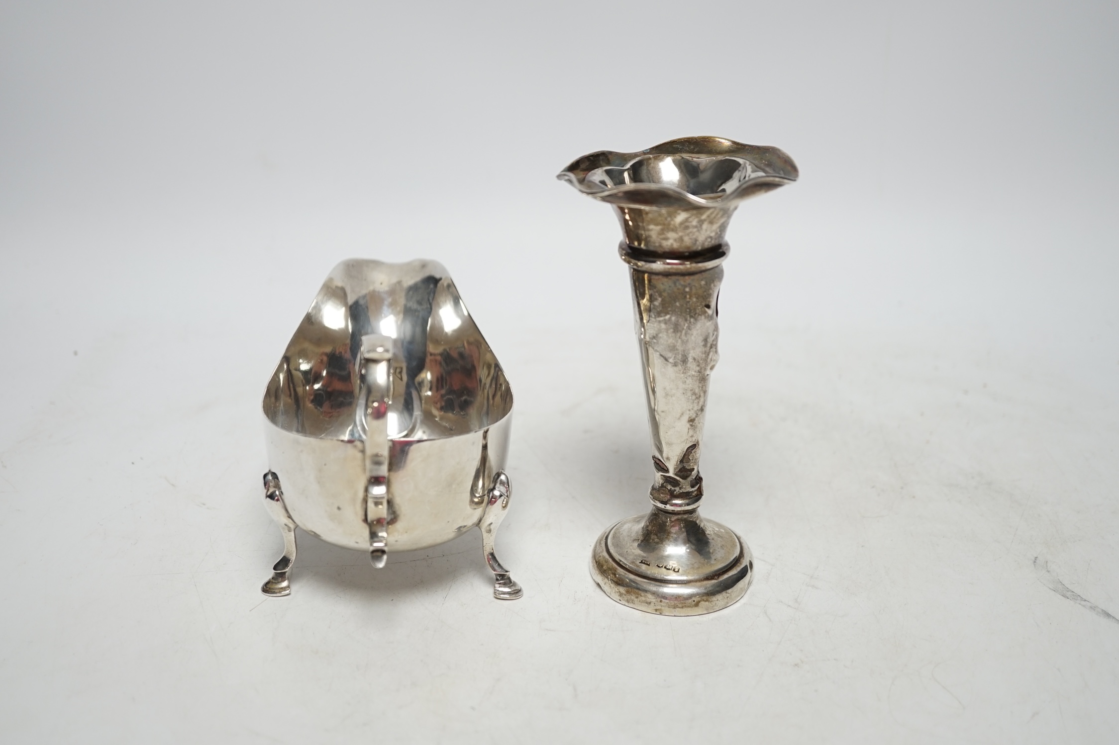 A George V silver sauceboat, Sheffield 1925, 14.5cm, 4.2oz and a similar silver mounted posy vase. Fair and poor condition.